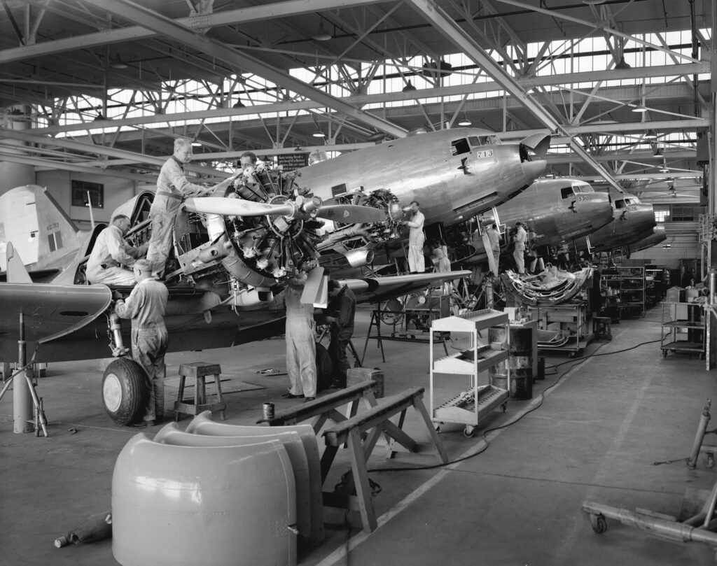 a black and white photo of men working on an airplane